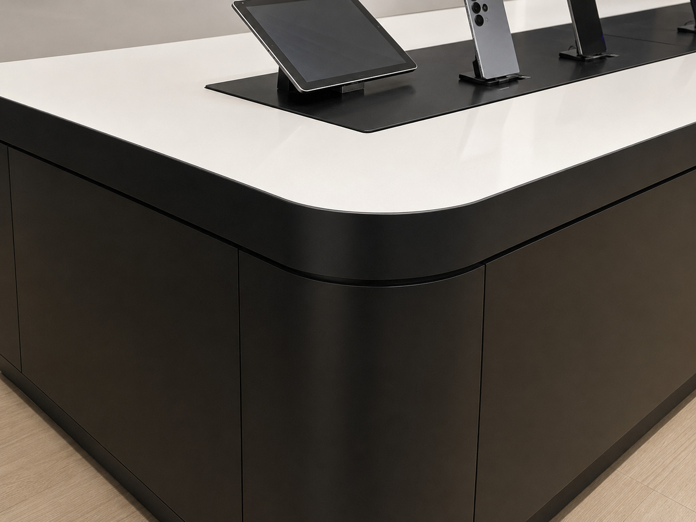 Close-up of rounded white countertop, black edge band and flush matte-black cabinet panels on Samsung mobile experience table
