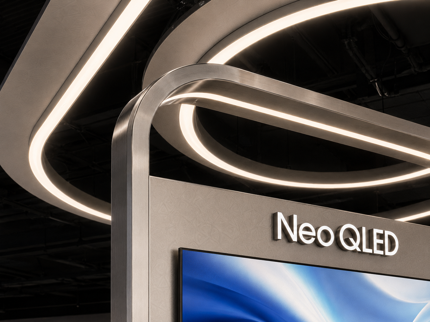 Close-up of rounded brushed-metal frame corner crossing layered illuminated ceiling rings on Samsung Vision AI display