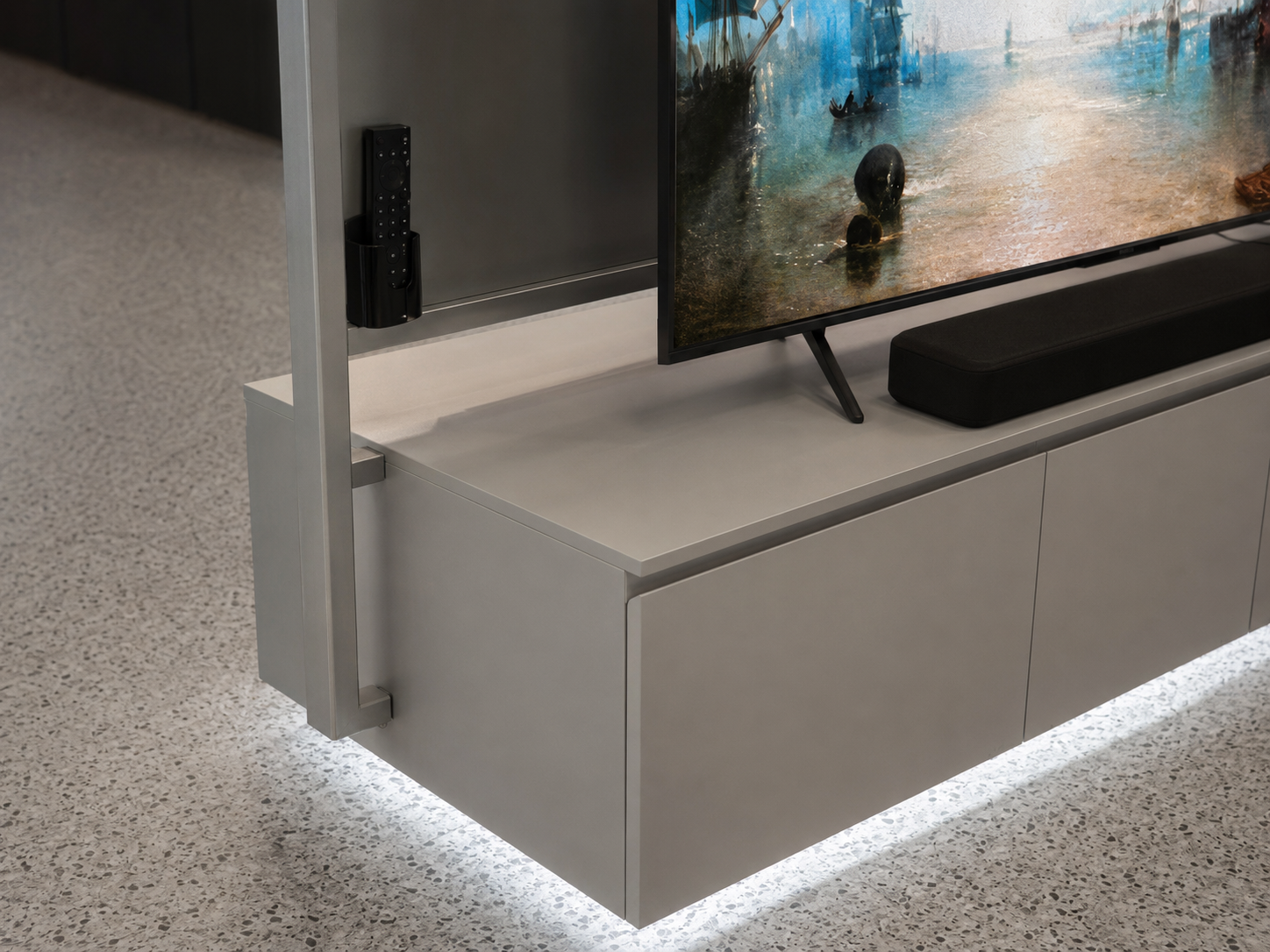 Close detail of TCL television display remote holder, screen support, cabinet joints and continuous under-cabinet lighting
